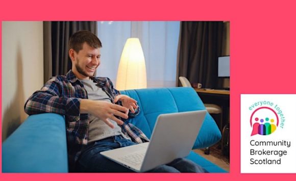 A man sits on a sofa doing a video call on his laptop