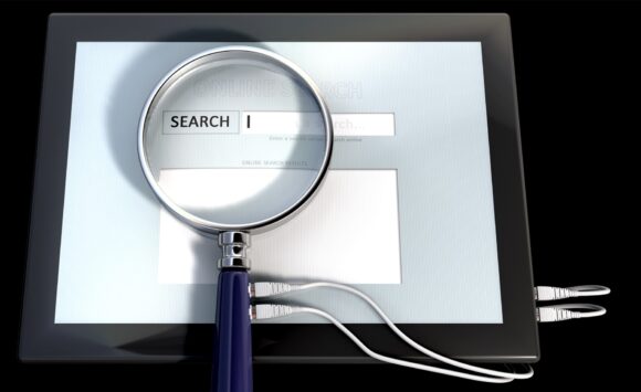 A picture of a magnifying glass over a computer screen with an online search bar displayed