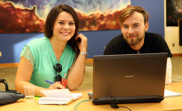 Two young people are working together at a laptop